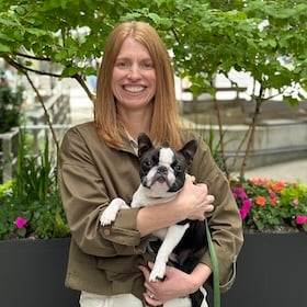 smiling woman holding a black and white small dog